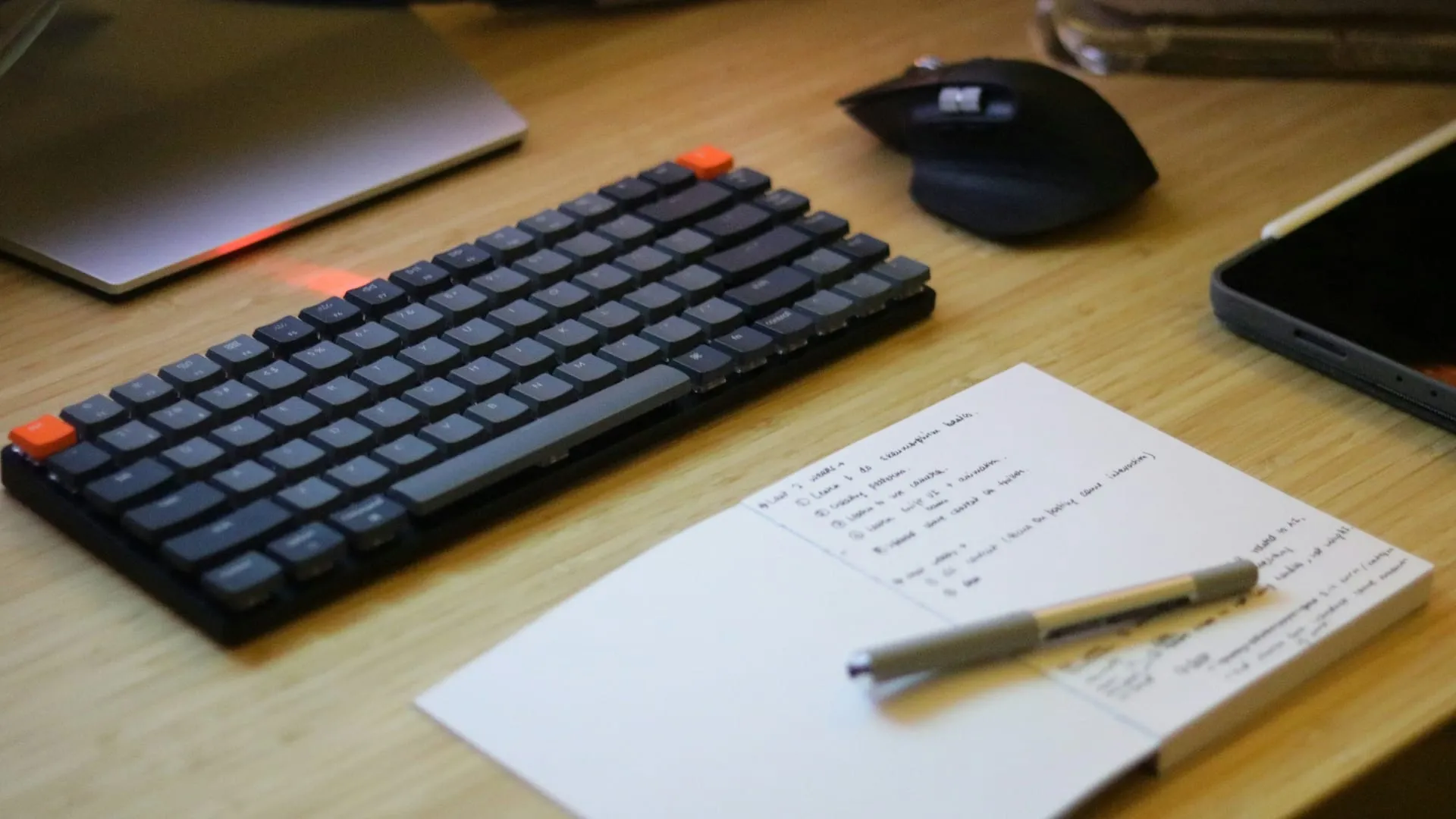 A clean desk with a phone, notebook and laptop ready for a call